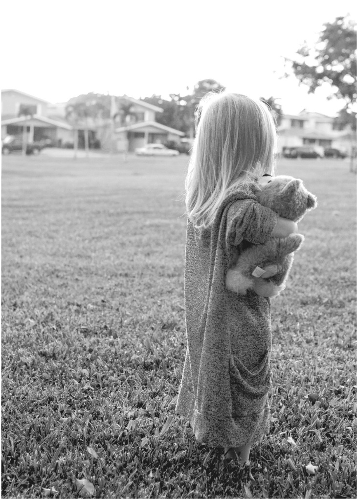 little girl holding wolf toy in gray sweater in honolulu hawaii during second birthday photos